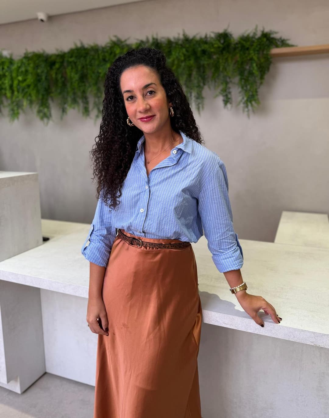 dra. julia pitangui apoiada na cadeira com o consultório ao fundo